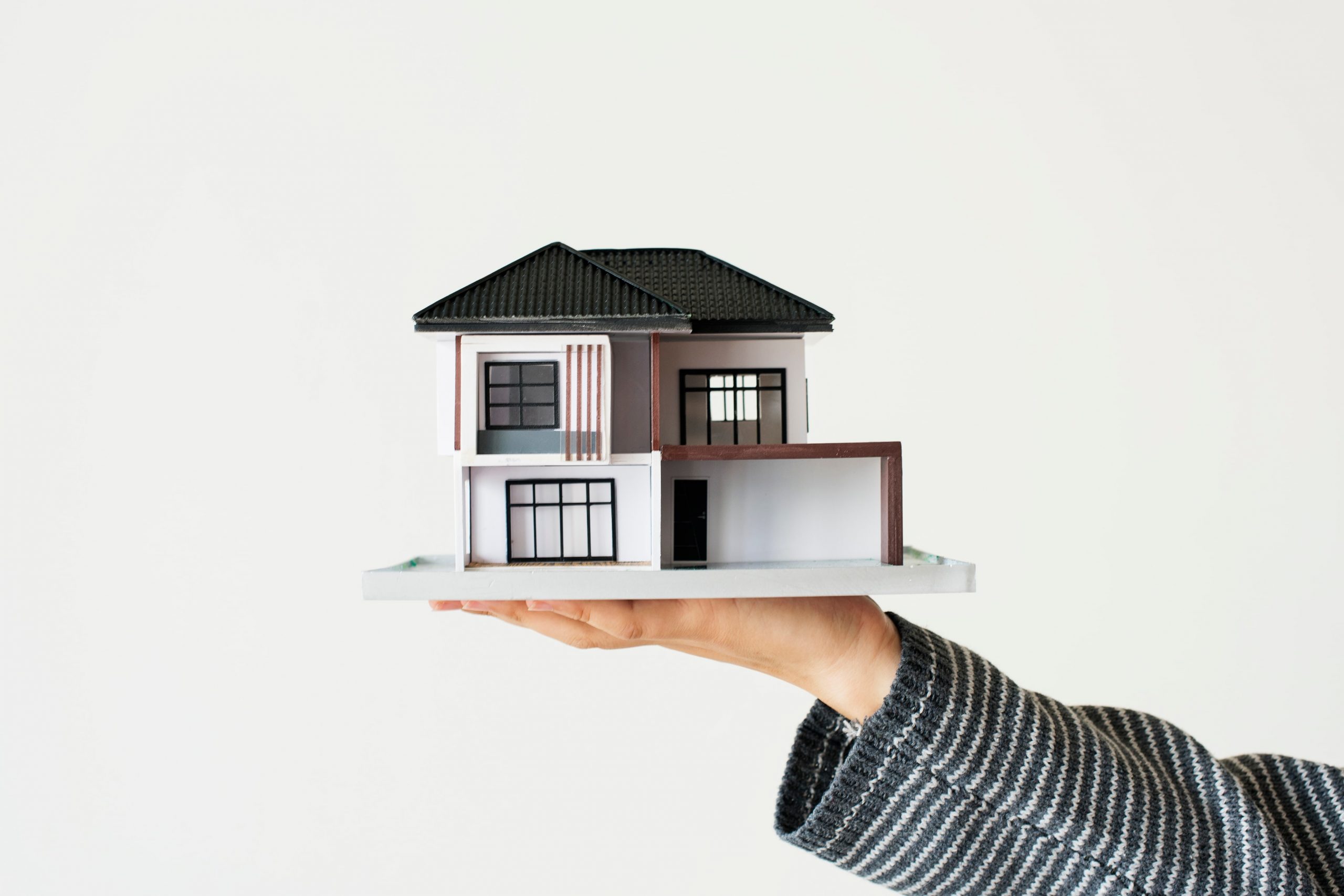 Hand holding a model house to represent property ownership and equity